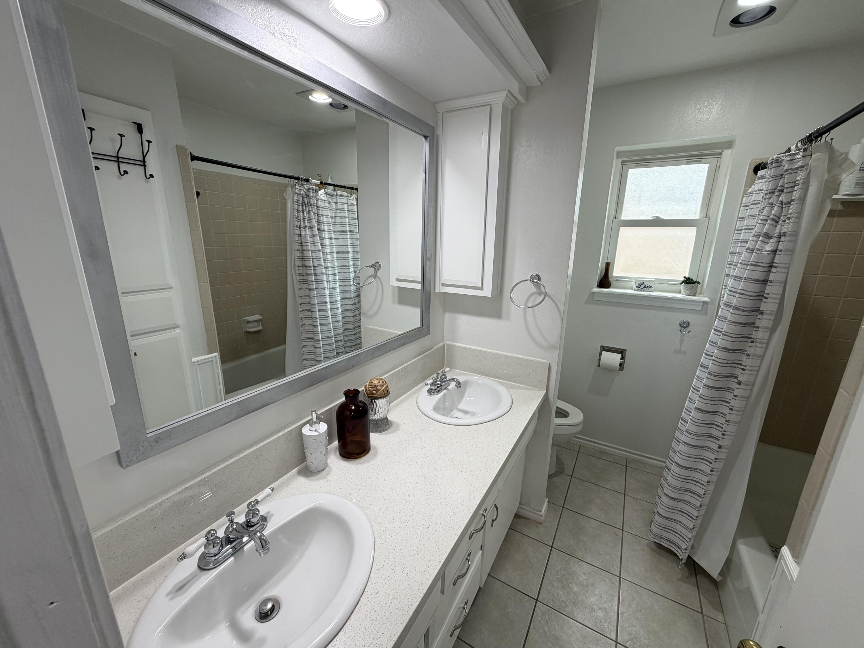 3236 94th Street Lubbock, TX 79423 - Photo 20 of 31 a bathroom with a sink a toilet and a mirror