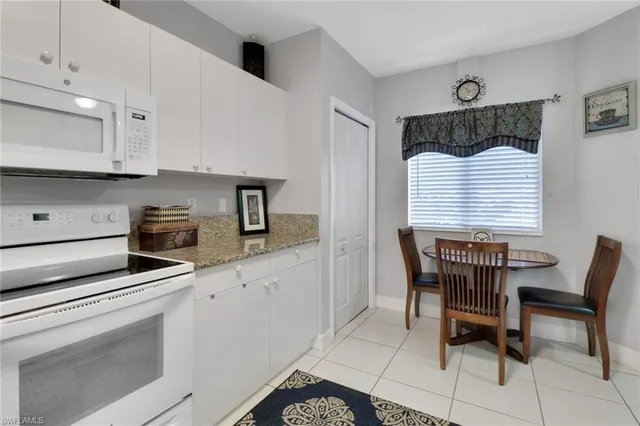 a kitchen with stainless steel appliances kitchen island granite countertop a table chairs and a refrigerator