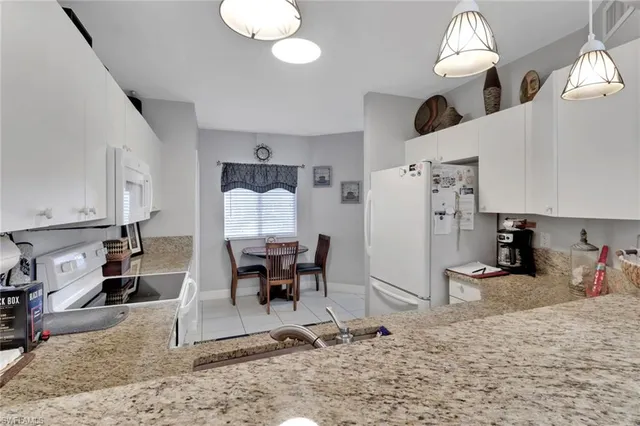 a kitchen with stainless steel appliances kitchen island granite countertop dining table chairs sink and cabinets