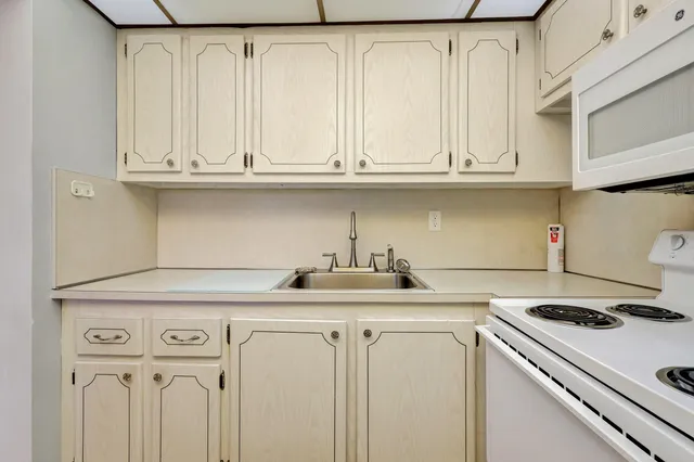 a kitchen with granite countertop white cabinets and a white stove