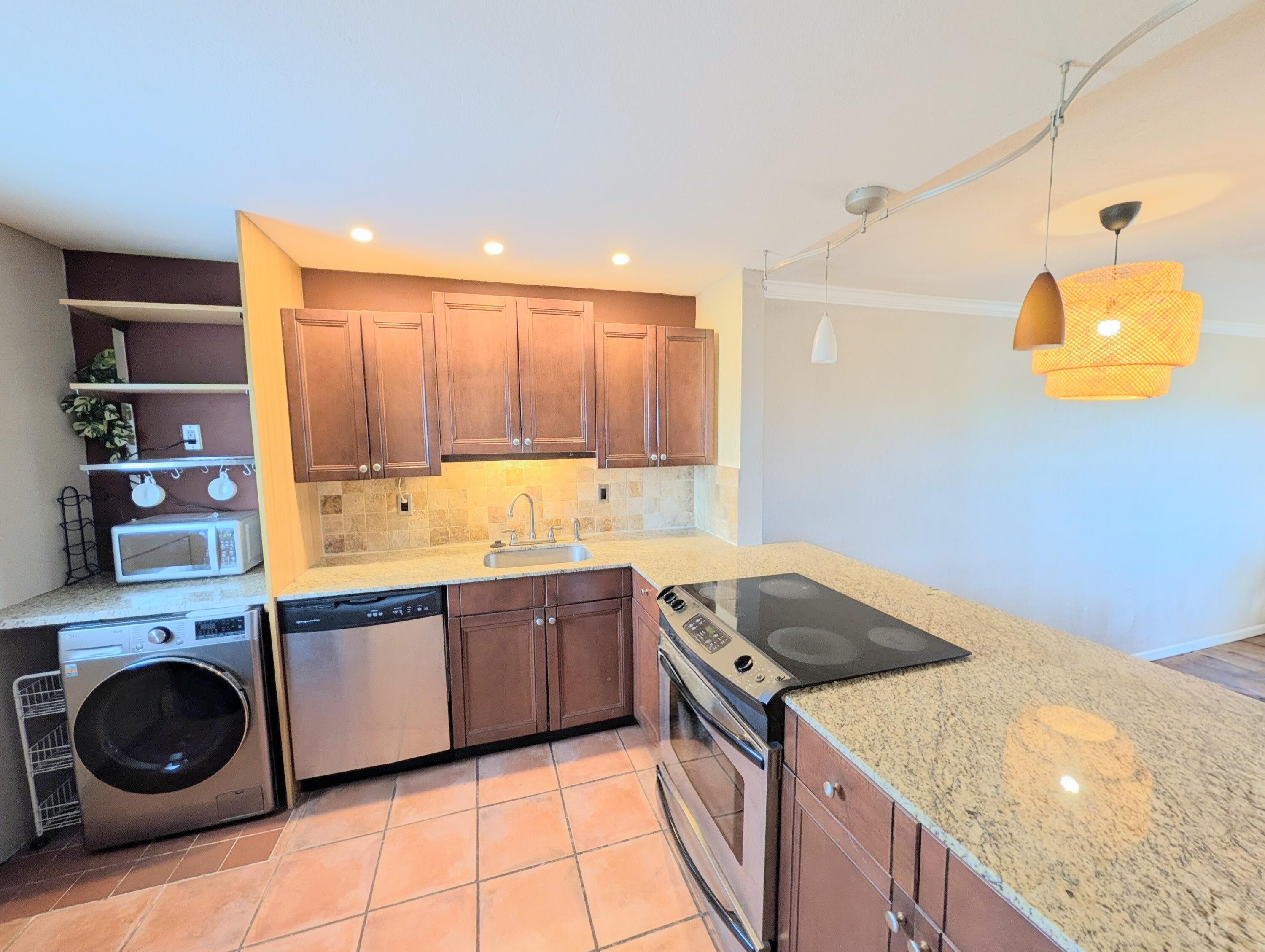 5700 Northwest 2nd Avenue, Unit 509 Boca Raton, FL 33487 - Photo 5 of 20 a kitchen with granite countertop a sink a stove and cabinets