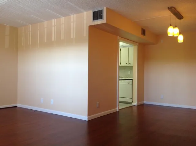 a view of an empty room with closet and wooden floor