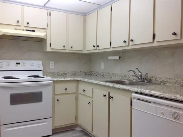a kitchen with granite countertop white cabinets and a stove