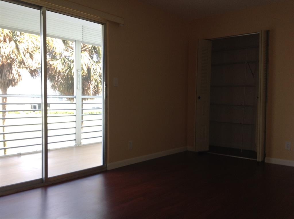 1805 Eleuthera Point, Unit J2 Coconut Creek, FL 33066 - Photo 10 of 22 a view of an empty room with wooden floor and a window