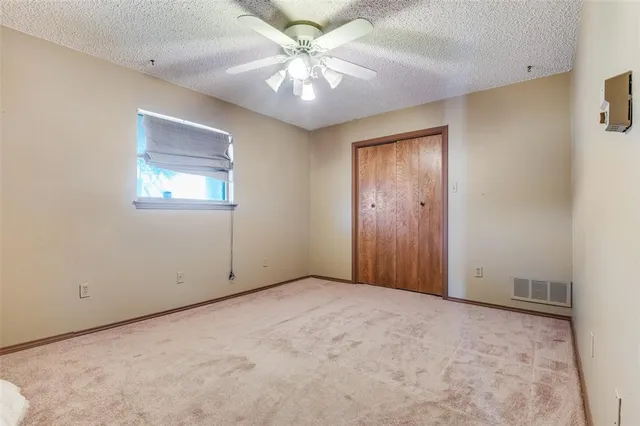 an empty room with windows and fan