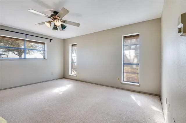 an empty room with windows and fan