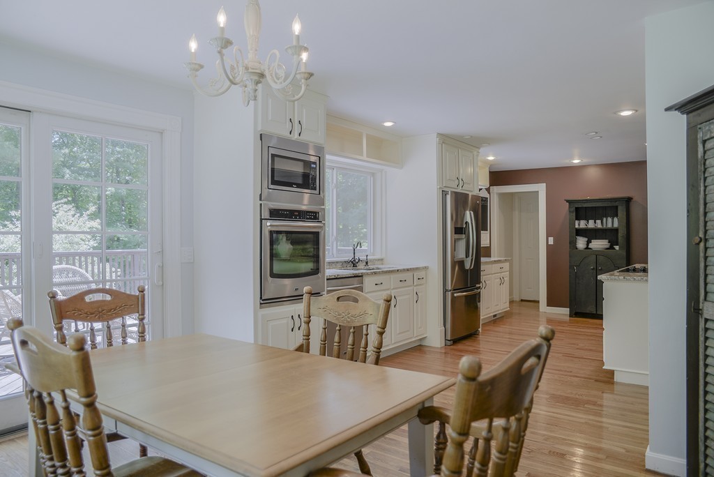 341 Main Street Boxford, MA 01921 - Photo 9 of 30 a kitchen with stainless steel appliances kitchen island granite countertop a refrigerator a stove a sink dishwasher with a dining table and chairs with wooden floor