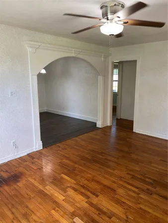 an empty room with wooden floor fan and windows