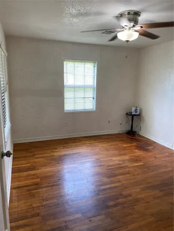 a view of empty room with wooden floor and fan