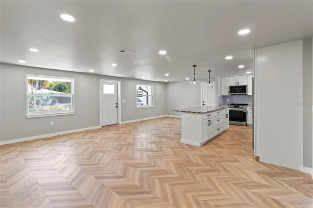 a large white kitchen with kitchen island a stove a sink a refrigerator and white cabinets with wooden floor