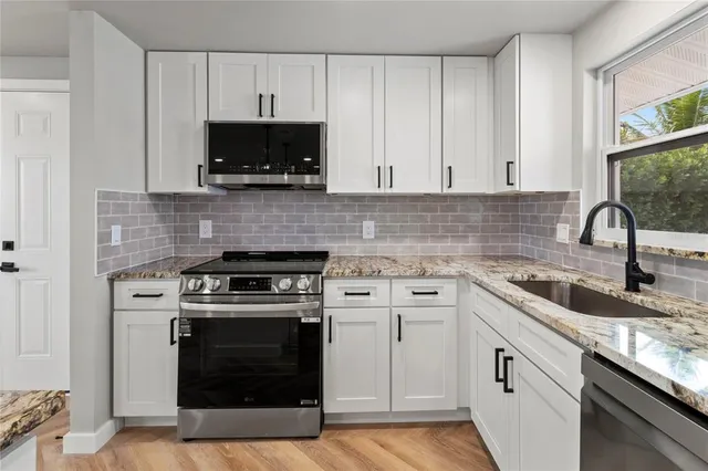 a kitchen with white cabinets and stainless steel appliances