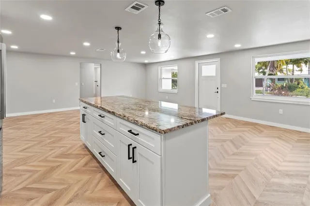 a kitchen with kitchen island granite countertop a stove and a sink with granite countertops