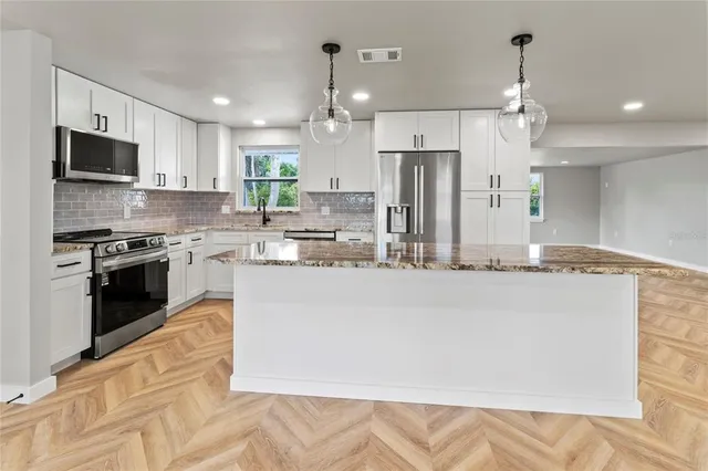 a kitchen with stainless steel appliances granite countertop a refrigerator a stove a sink dishwasher a oven and white cabinets with wooden floor
