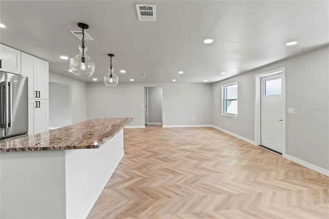 a large white kitchen with a granite countertop faucet a sink and a refrigerator