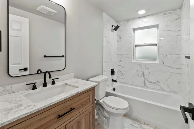 a bathroom with a granite countertop toilet sink and mirror