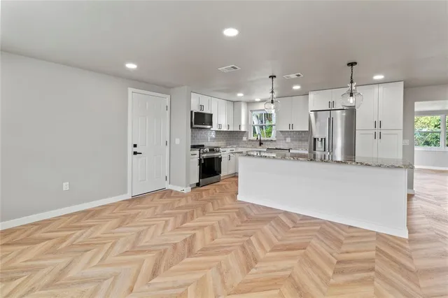 a large white kitchen with kitchen island a sink a center island stainless steel appliances and a cabinets