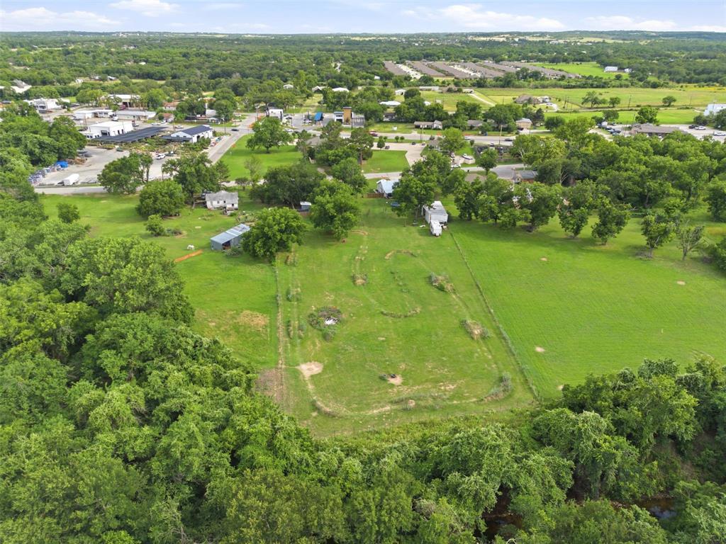 308 West 1st Street Springtown, TX 76082 - Photo 36 of 39 Expansive green acreage featuring mature trees and a distant road with commercial structures