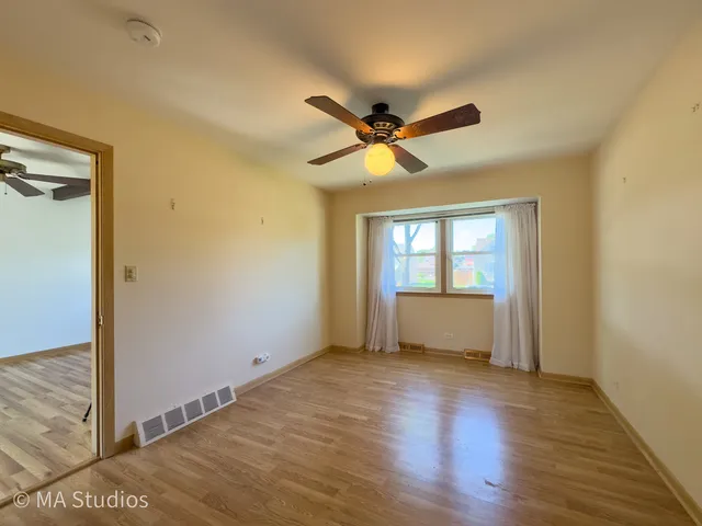 a view of empty room with wooden floor and fan