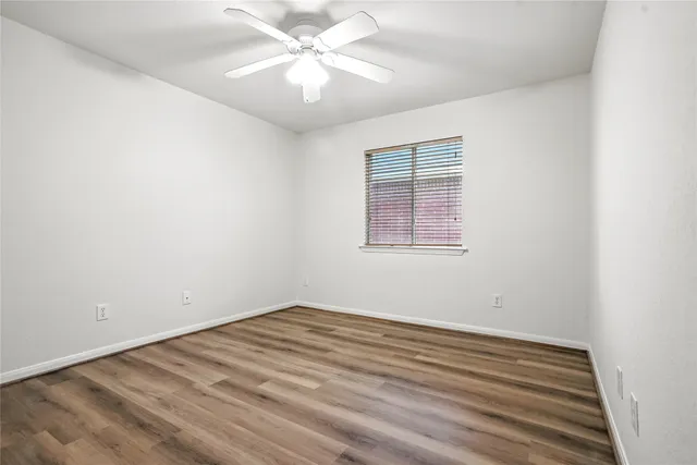 an empty room with a window and ceiling fan
