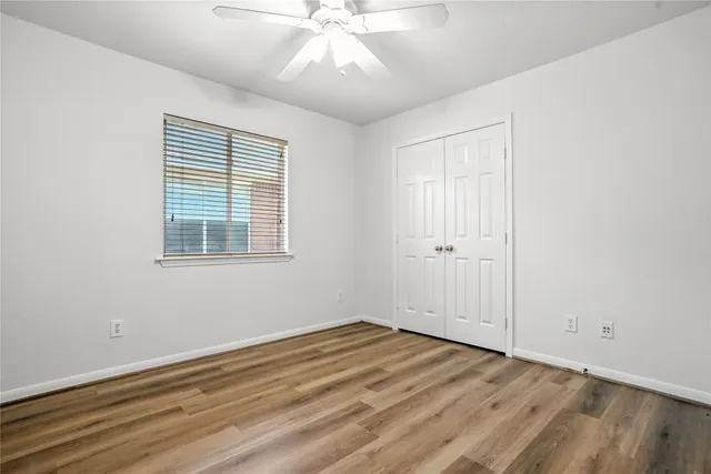 a view of empty room with wooden floor and fan