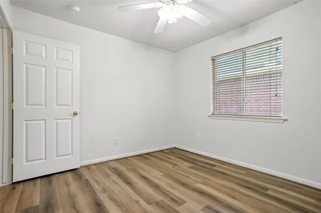 a view of empty room with wooden floor and fan