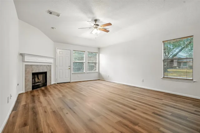 a view of empty room with wooden floor and fan