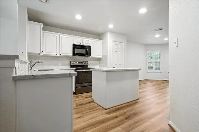 a kitchen with kitchen island a sink stainless steel appliances and cabinets