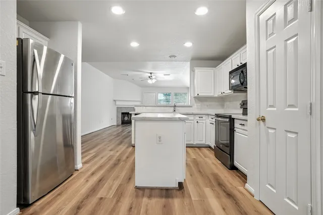 a kitchen with stainless steel appliances a refrigerator a sink and white cabinets