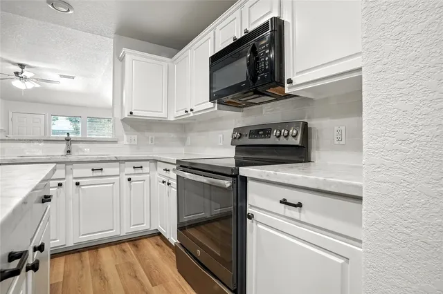 a kitchen with stainless steel appliances white cabinets and a stove top oven