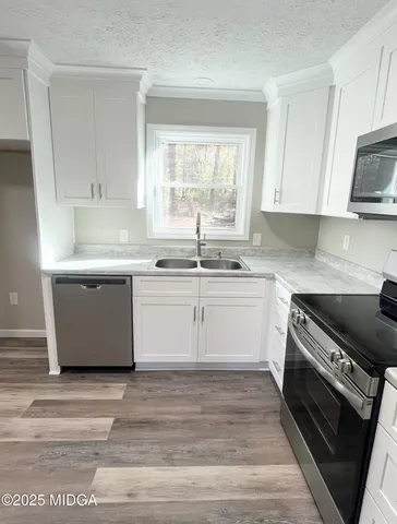 a kitchen with a stove white cabinets wooden floor and a sink