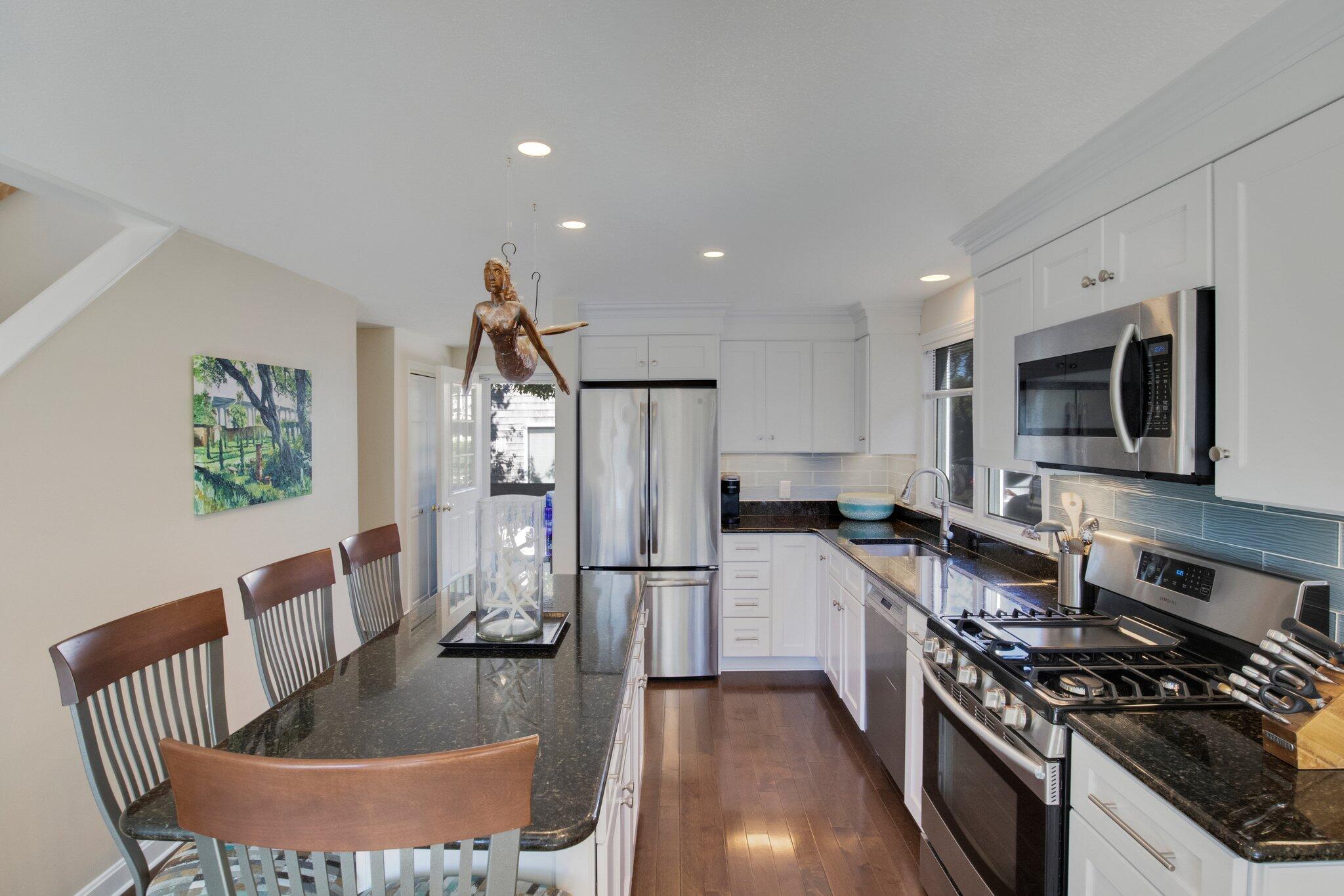 4 Willow Drive, Unit 9 Provincetown, MA 02657 - Photo 8 of 25 a kitchen with stainless steel appliances granite countertop a refrigerator a stove a sink a microwave a dining table and chairs with wooden floor
