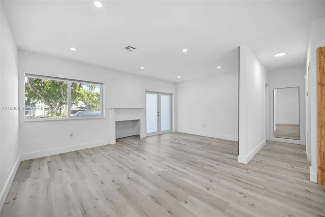 a view of empty room with wooden floor and kitchen