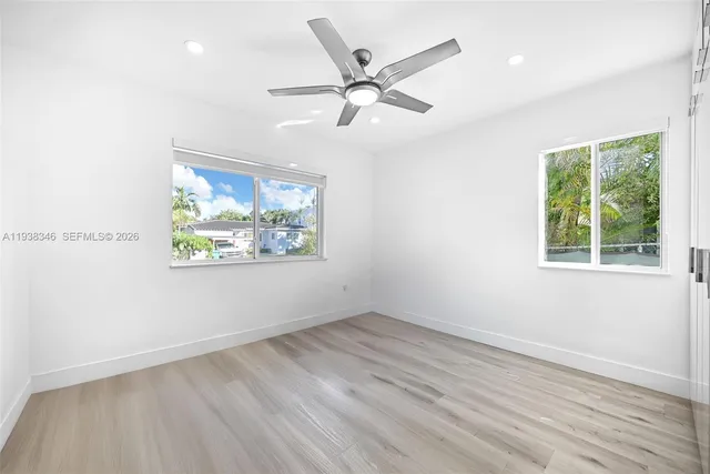 an empty room with wooden floor fan and windows