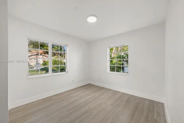 an empty room with wooden floor and windows