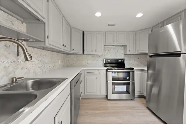 a kitchen with a refrigerator sink and white cabinets