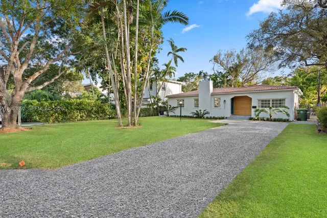 a front view of a house with garden and trees
