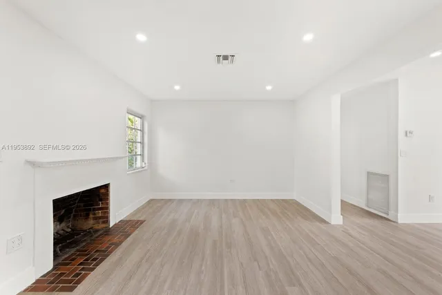 a view of empty room with wooden floor and fireplace