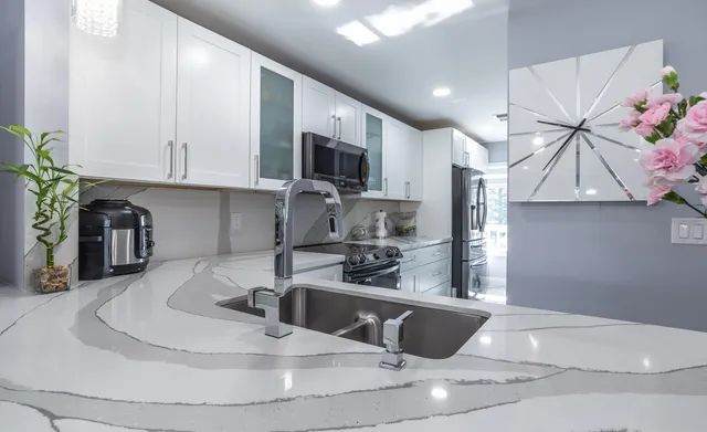 a kitchen with stainless steel appliances kitchen island granite countertop a sink a stove and a microwave