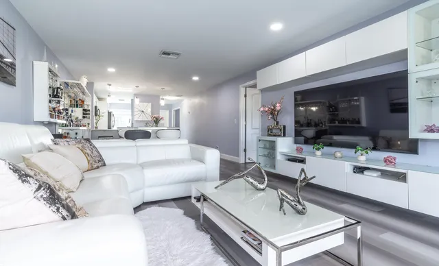 a living room with furniture a flat screen tv and kitchen view