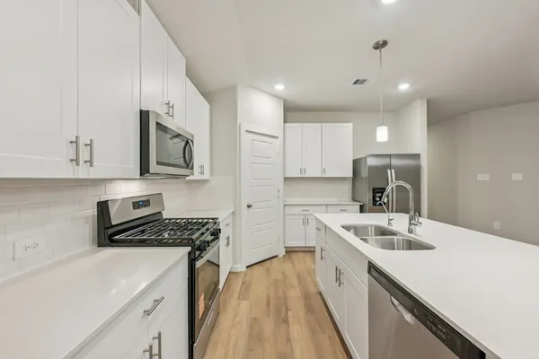 a kitchen with stainless steel appliances a sink a stove a microwave a sink a refrigerator and cabinets