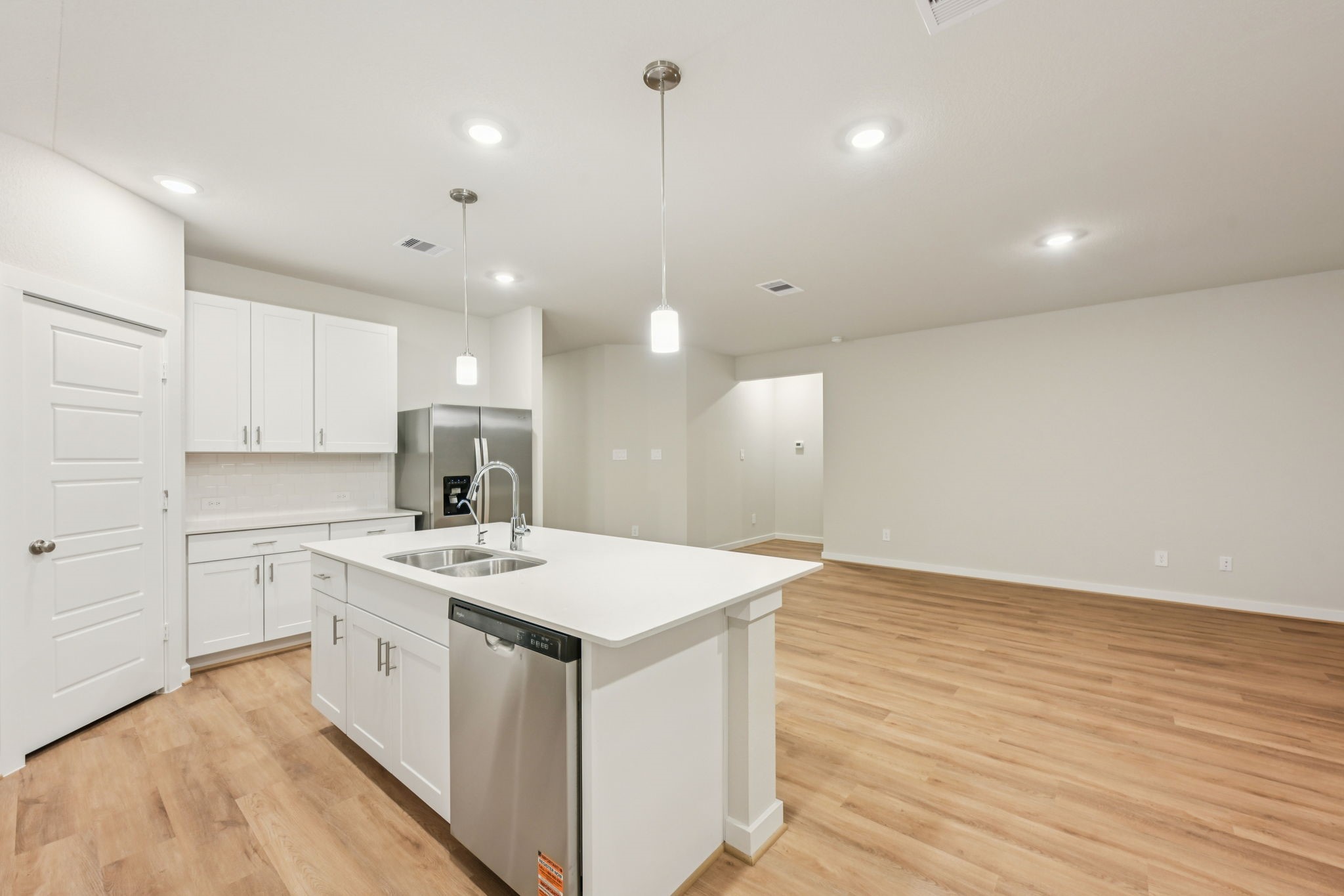 1637 Hopson Ranch Drive Conroe, TX 77301 - Photo 12 of 39 a kitchen with a sink a stove a refrigerator and white cabinets with wooden floor