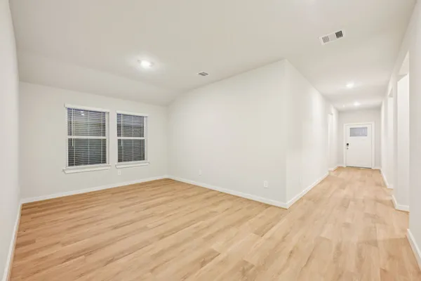 a view of an empty room with wooden floor and a window