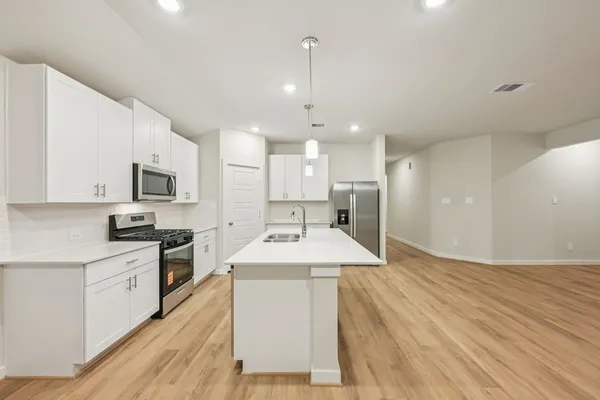 a room with kitchen island a sink stainless steel appliances and cabinets