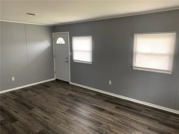 an empty room with wooden floor and windows