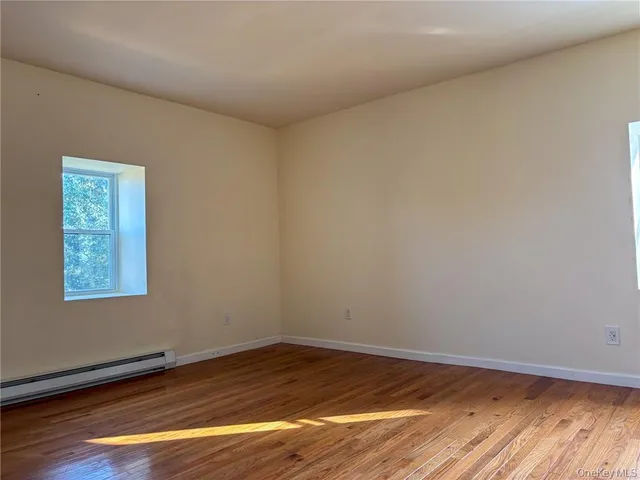 a view of an empty room and wooden floor and a window