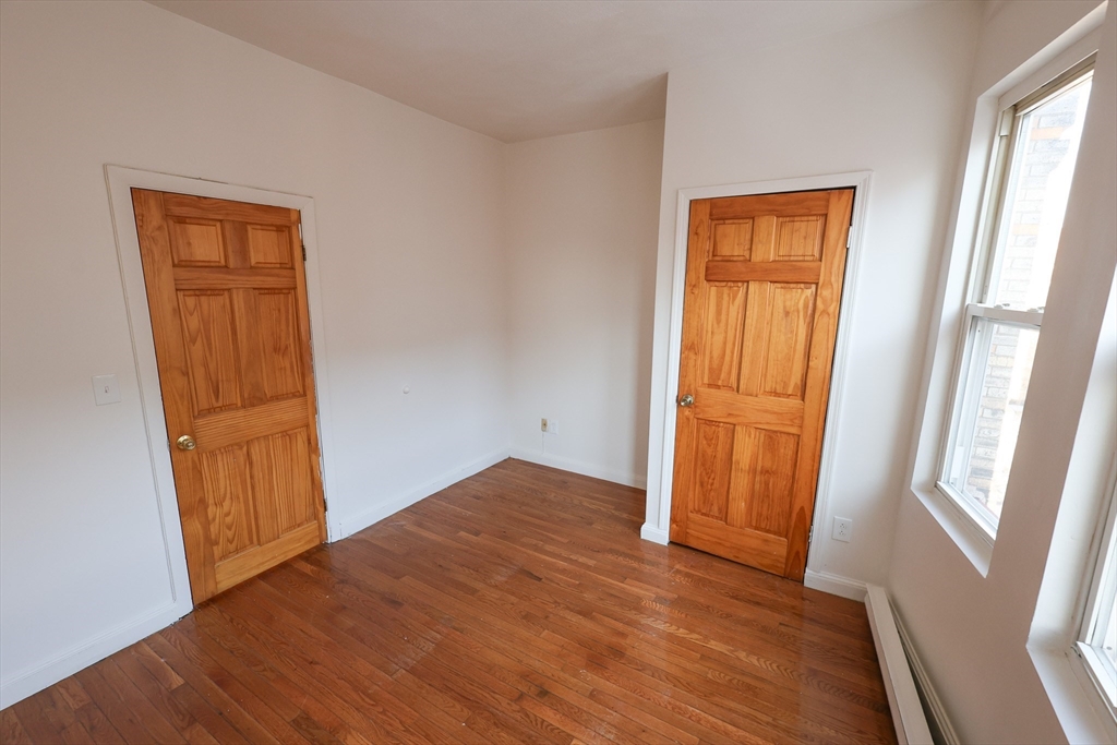 1 Kenilworth Street, Unit 3 Boston, MA 02119 - Photo 7 of 10 an empty room with wooden floor and windows