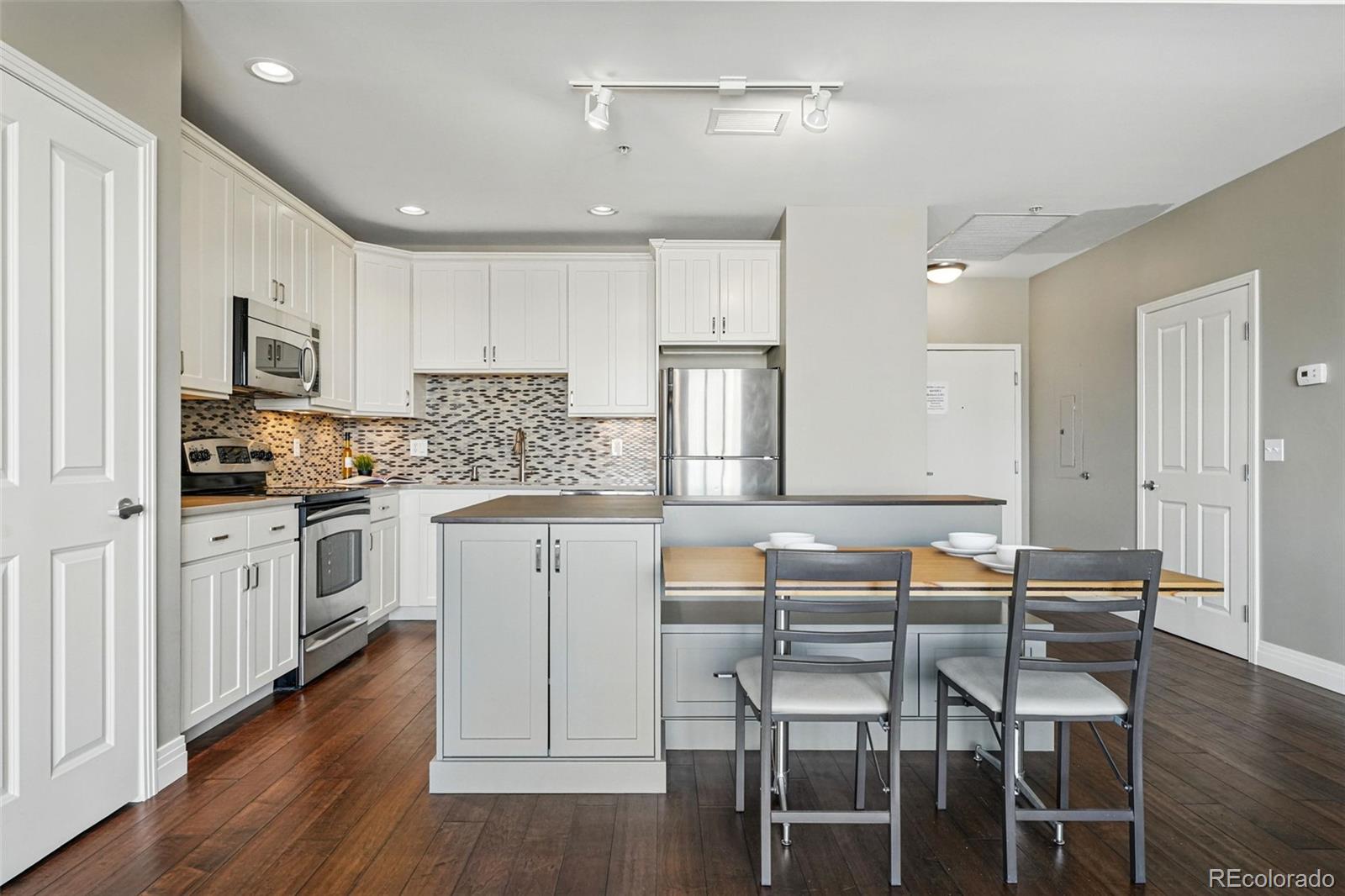 1950 Logan Street, Unit 1109 Denver, CO 80203 - Photo 3 of 49 a kitchen with a table chairs refrigerator and cabinets