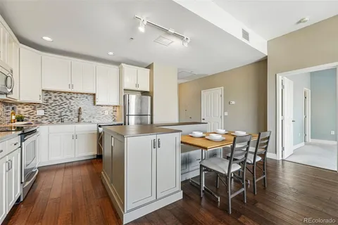 a kitchen with stainless steel appliances kitchen island granite countertop wooden floors and white cabinets