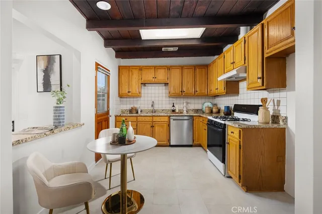 a kitchen with granite countertop a sink stainless steel appliances wooden cabinets and a window