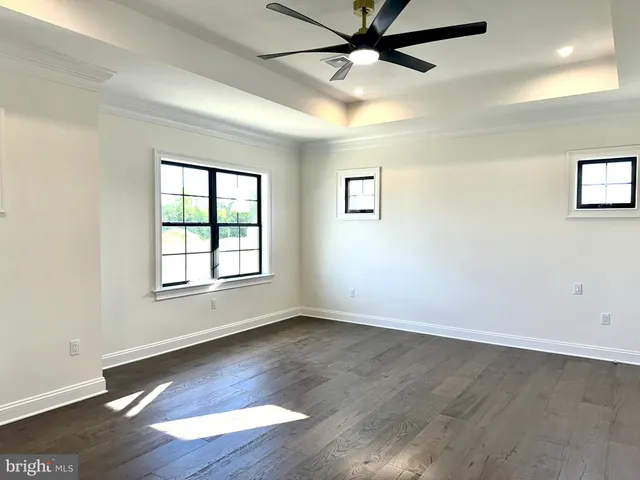 an empty room with wooden floor fan and windows